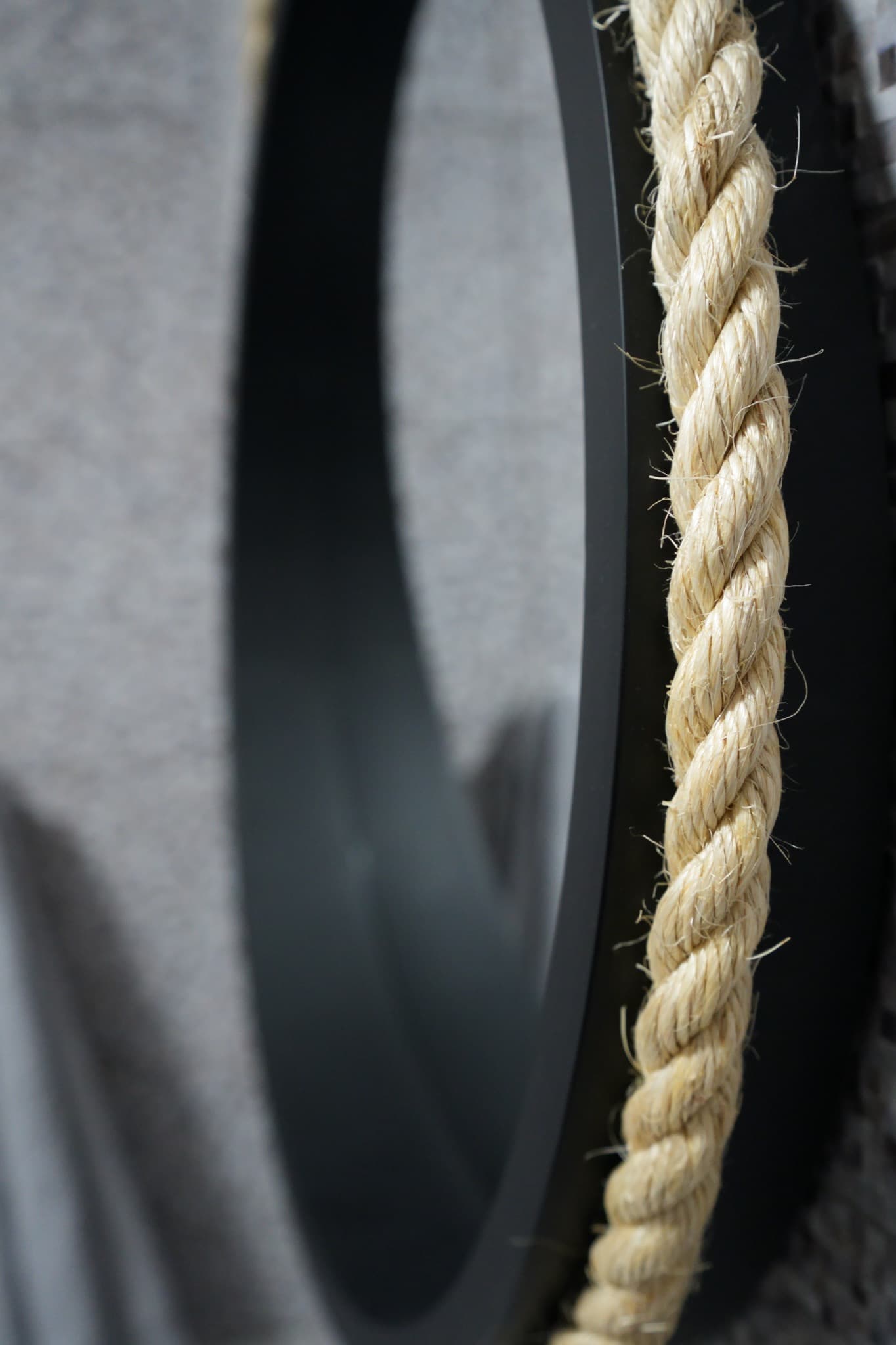 Close-up rope-edged black round mirror on bathroom mosaic tile wall