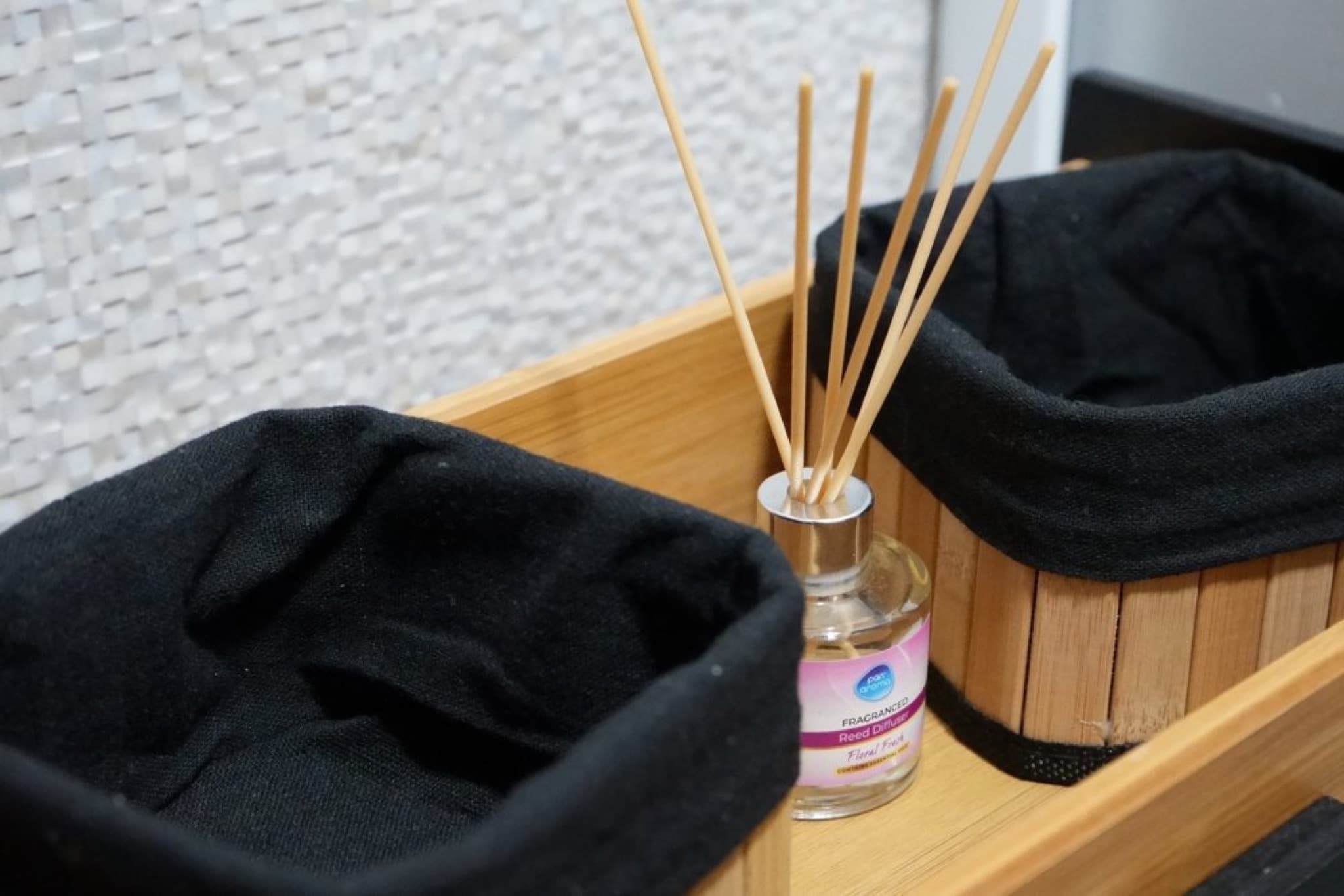 Reed diffuser with rattan sticks between two bamboo baskets with black lining