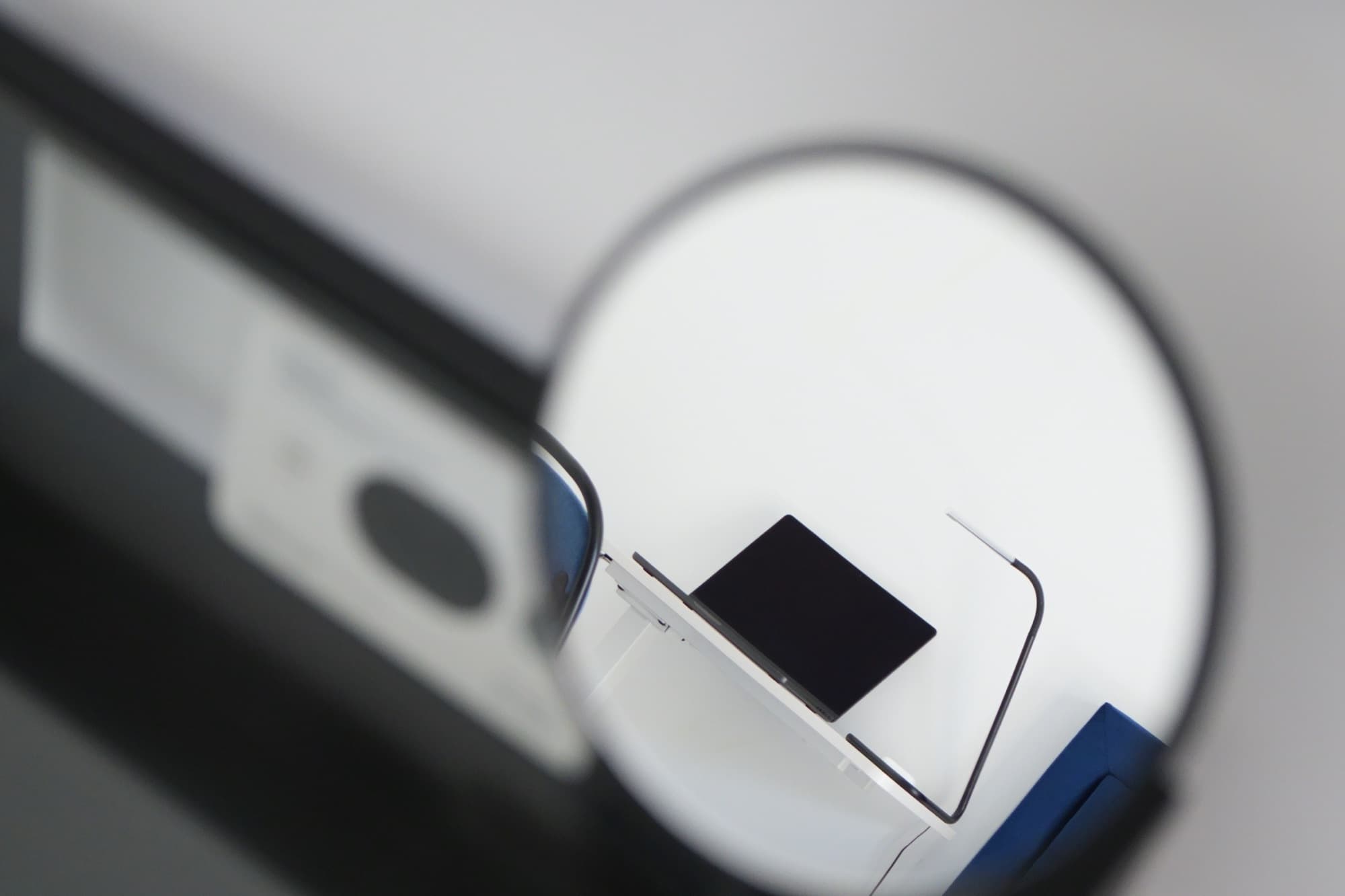 Desk and laptop reflected in round tabletop mirror beside blue headboard