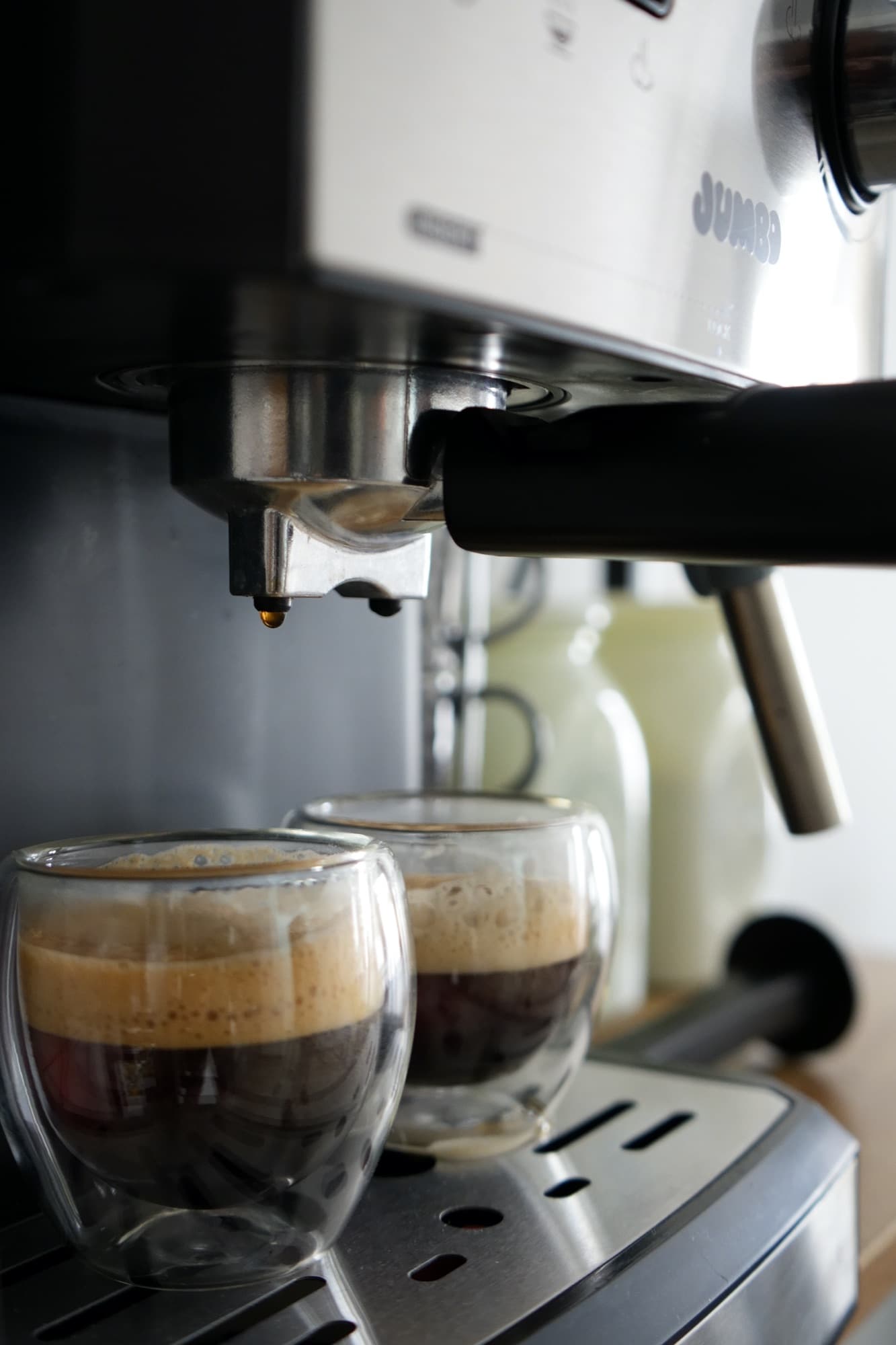 Espresso machine pouring coffee into two double-walled glass cups