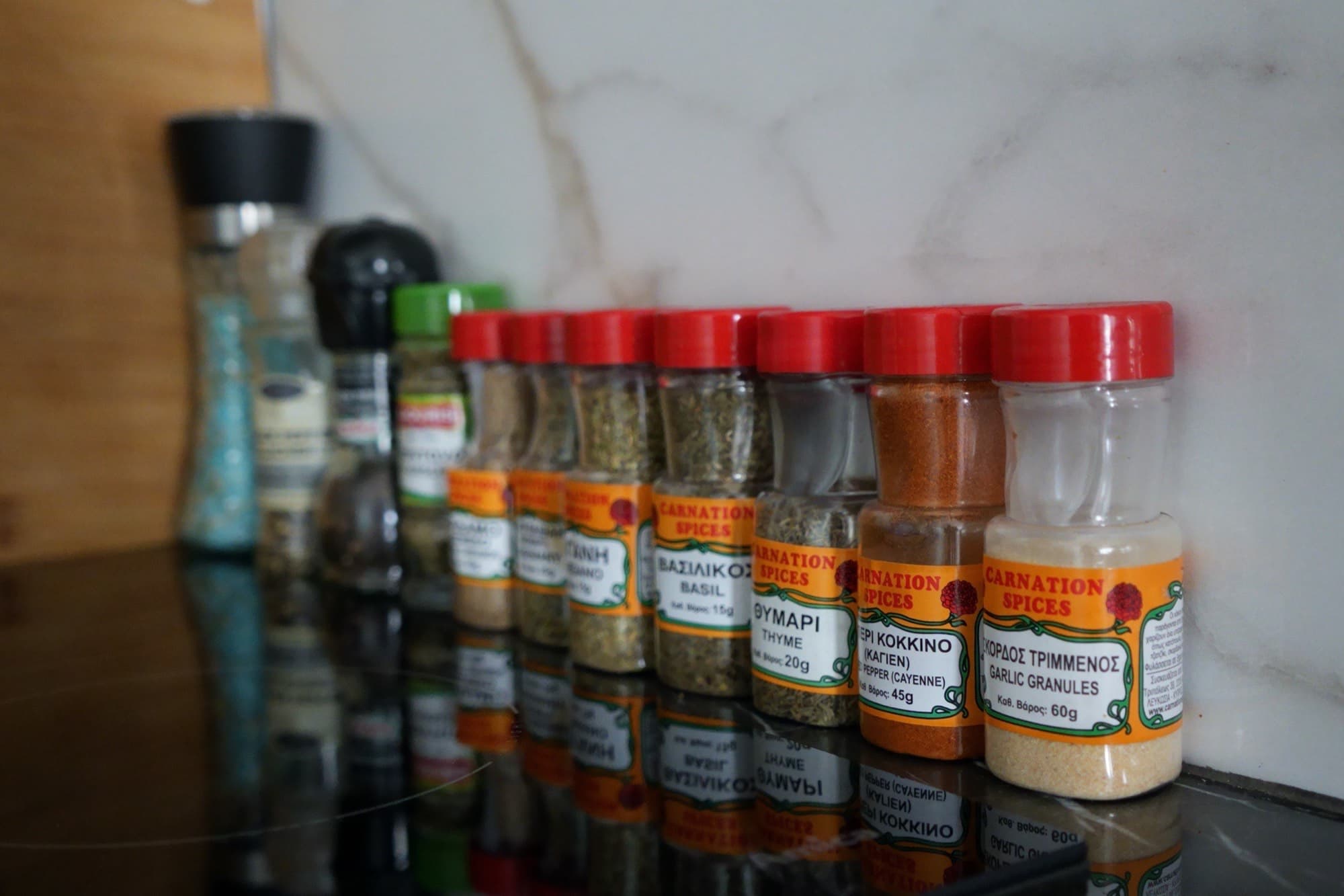Spice jars with red lids lined on black kitchen countertop
