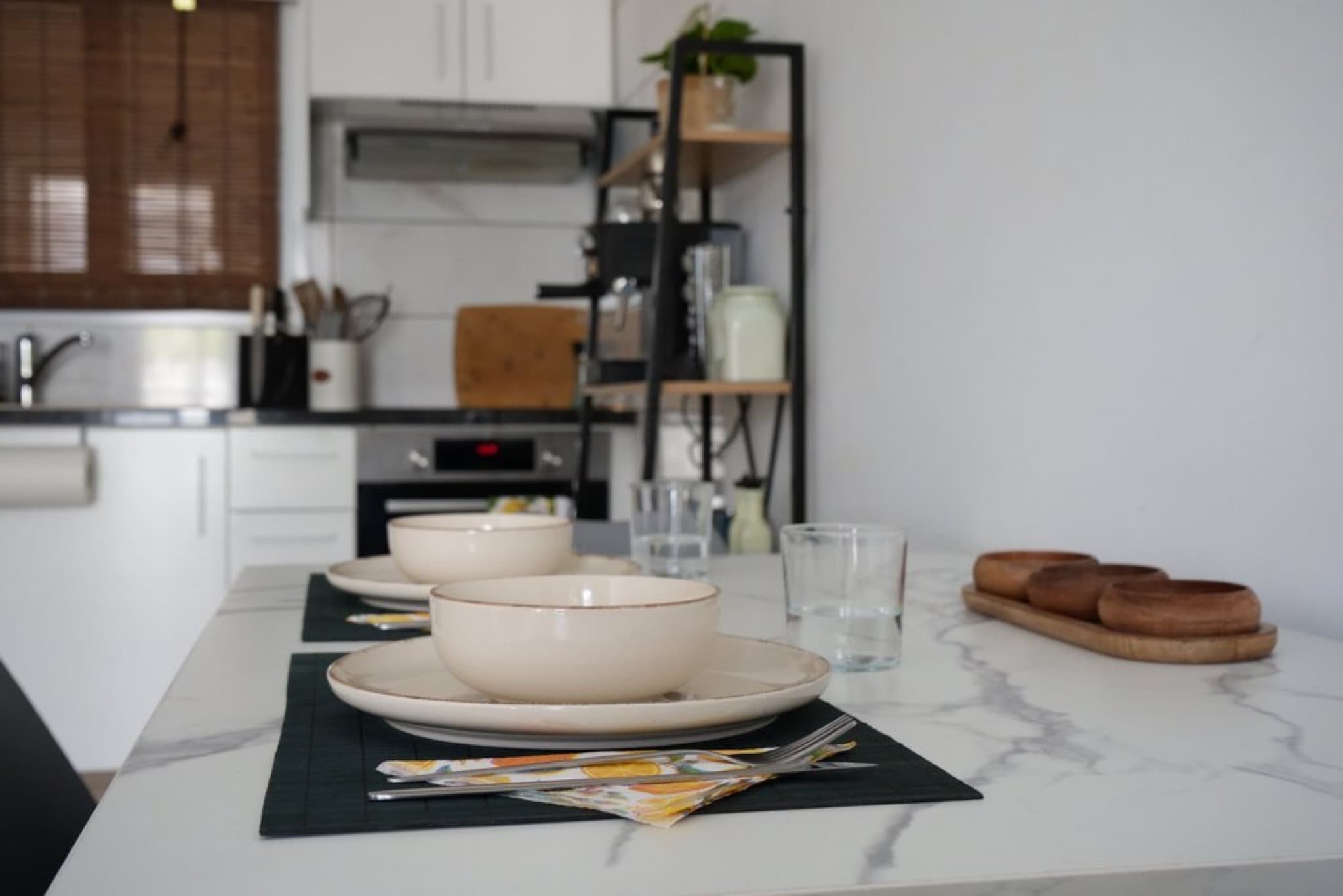 White marble dining table set with beige ceramic plate, bowl, water glass, and cutlery