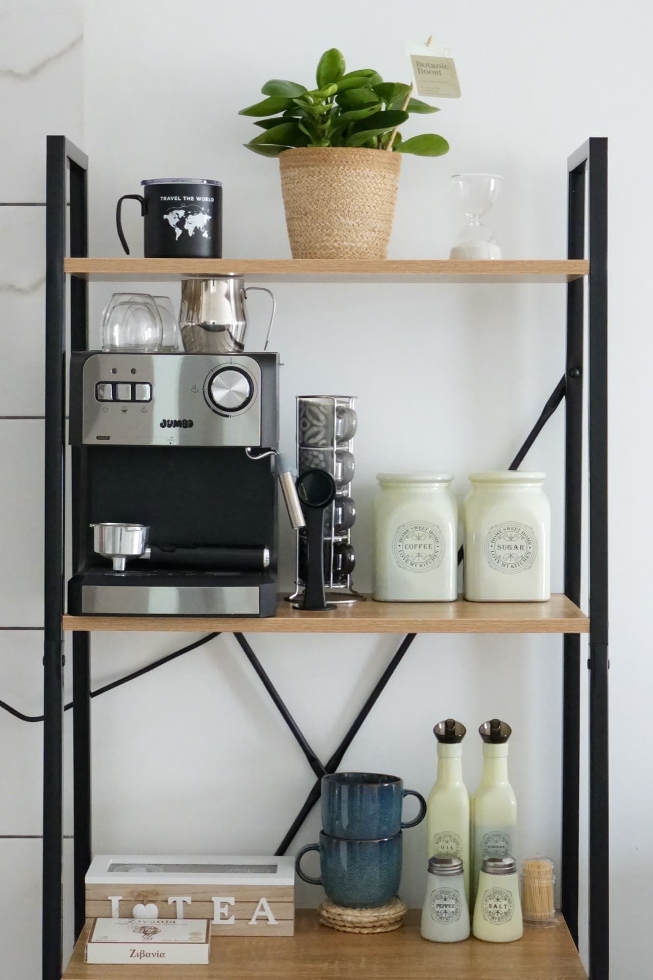 Overhead view of black metal shelf with espresso machine, ceramic mugs, and green bottles