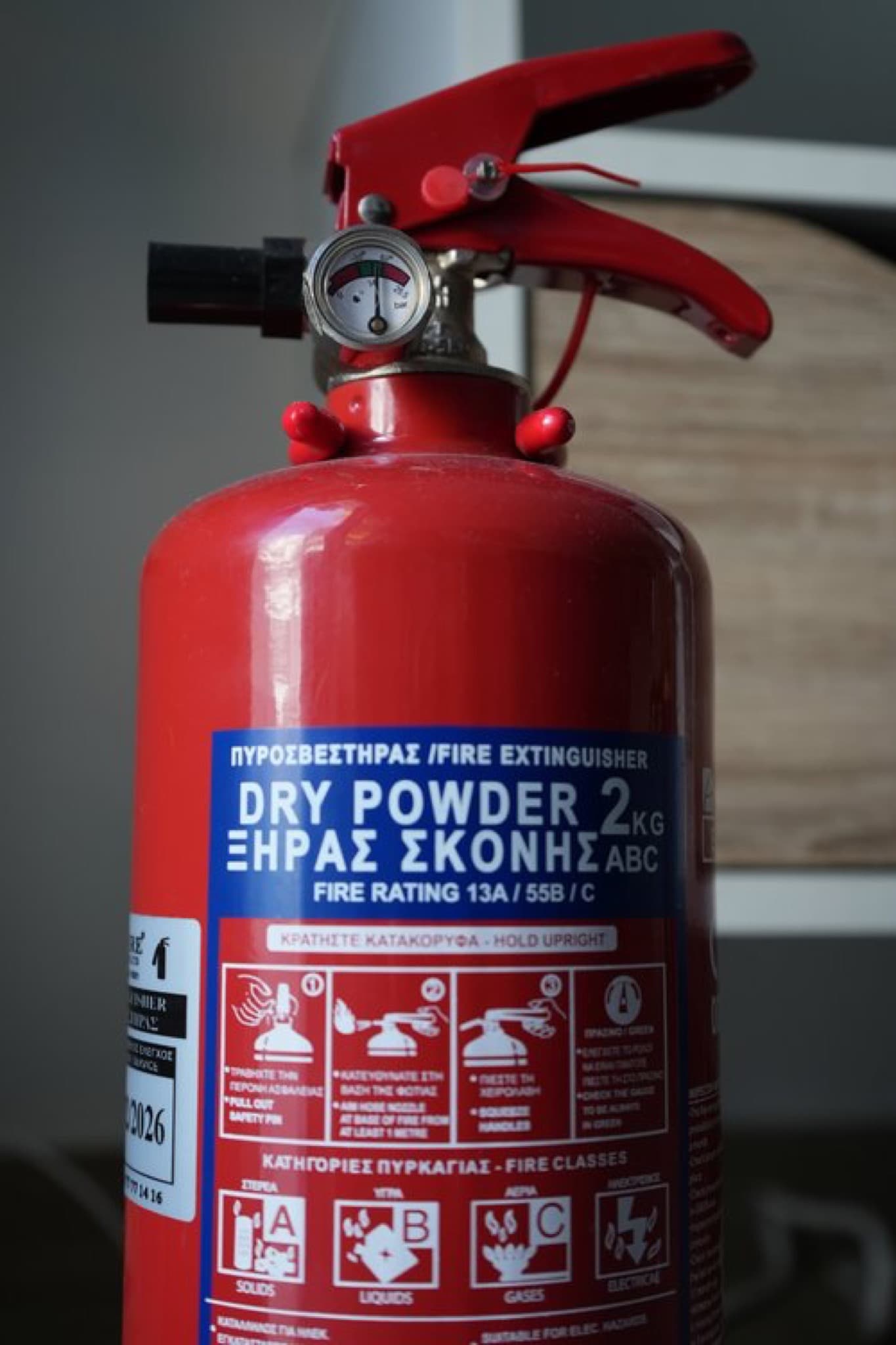 Close-up label of red 2 kg ABC dry powder fire extinguisher showing gauge