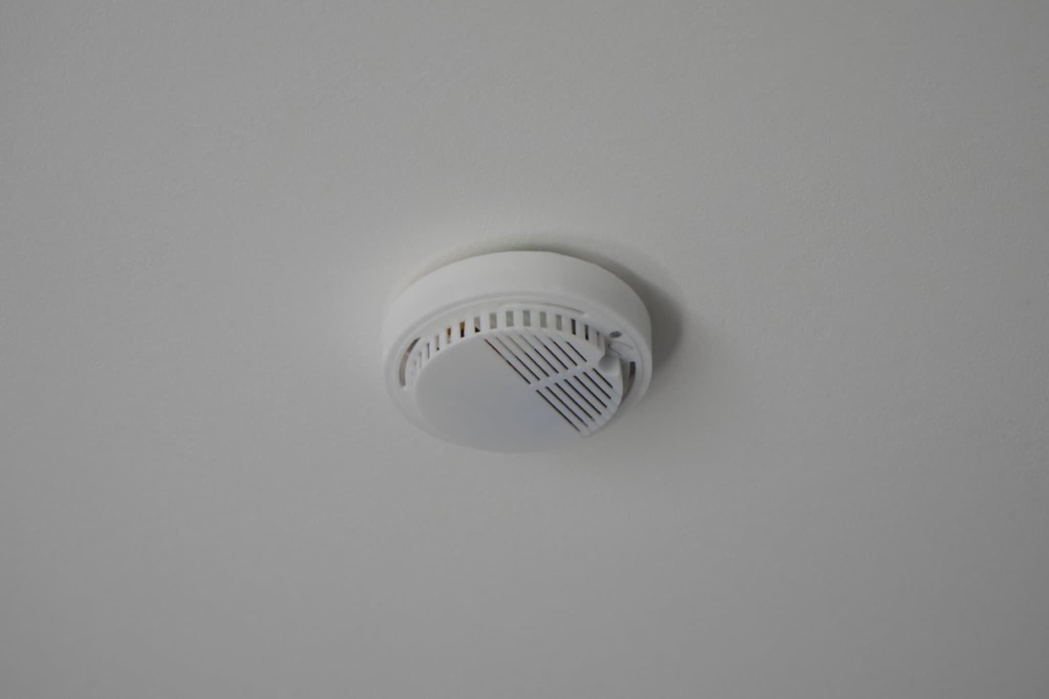 White round smoke detector with ventilation grille mounted flush on white ceiling
