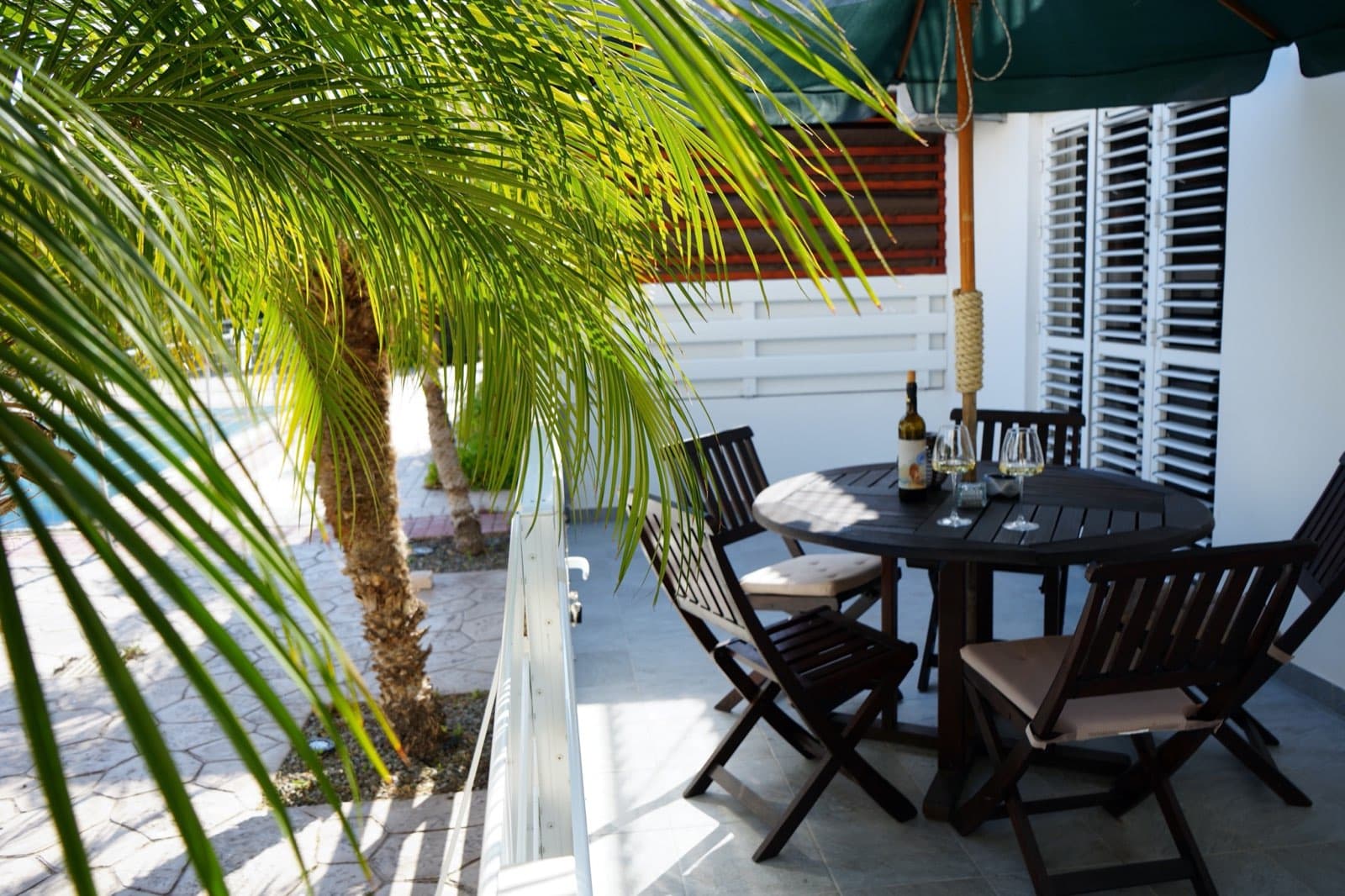 Dark wooden outdoor table and chairs with ashtray under green umbrella