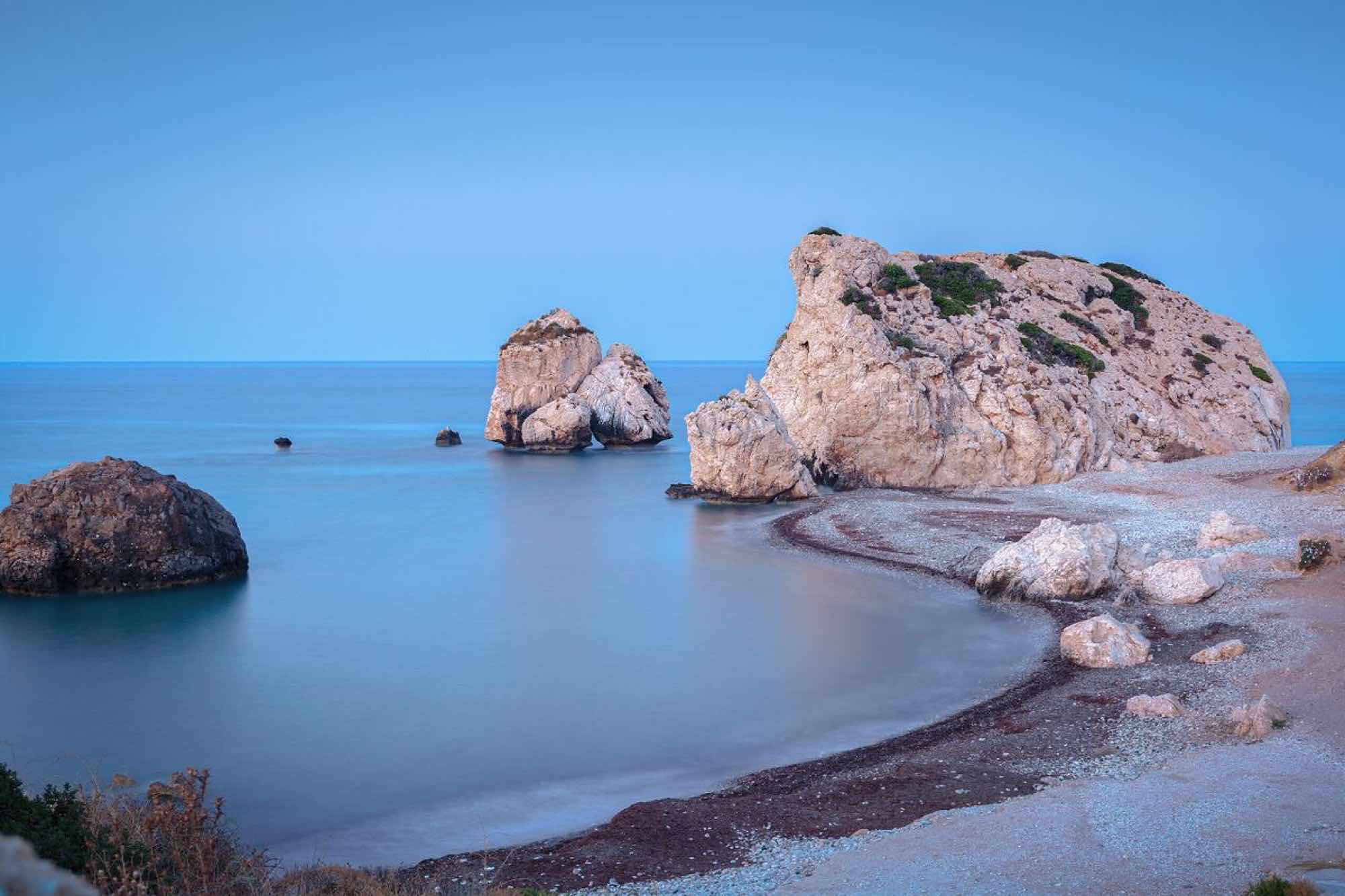 Aphrodite's Rock sea stacks rising from calm water at dusk