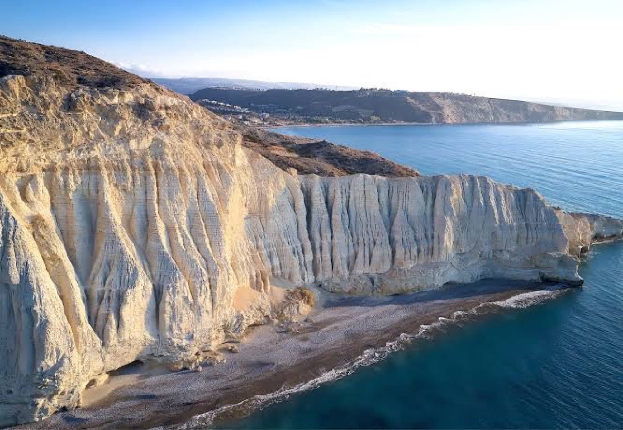 Ridged white chalk cliffs of Cape Aspro dropping to a narrow pebble beach