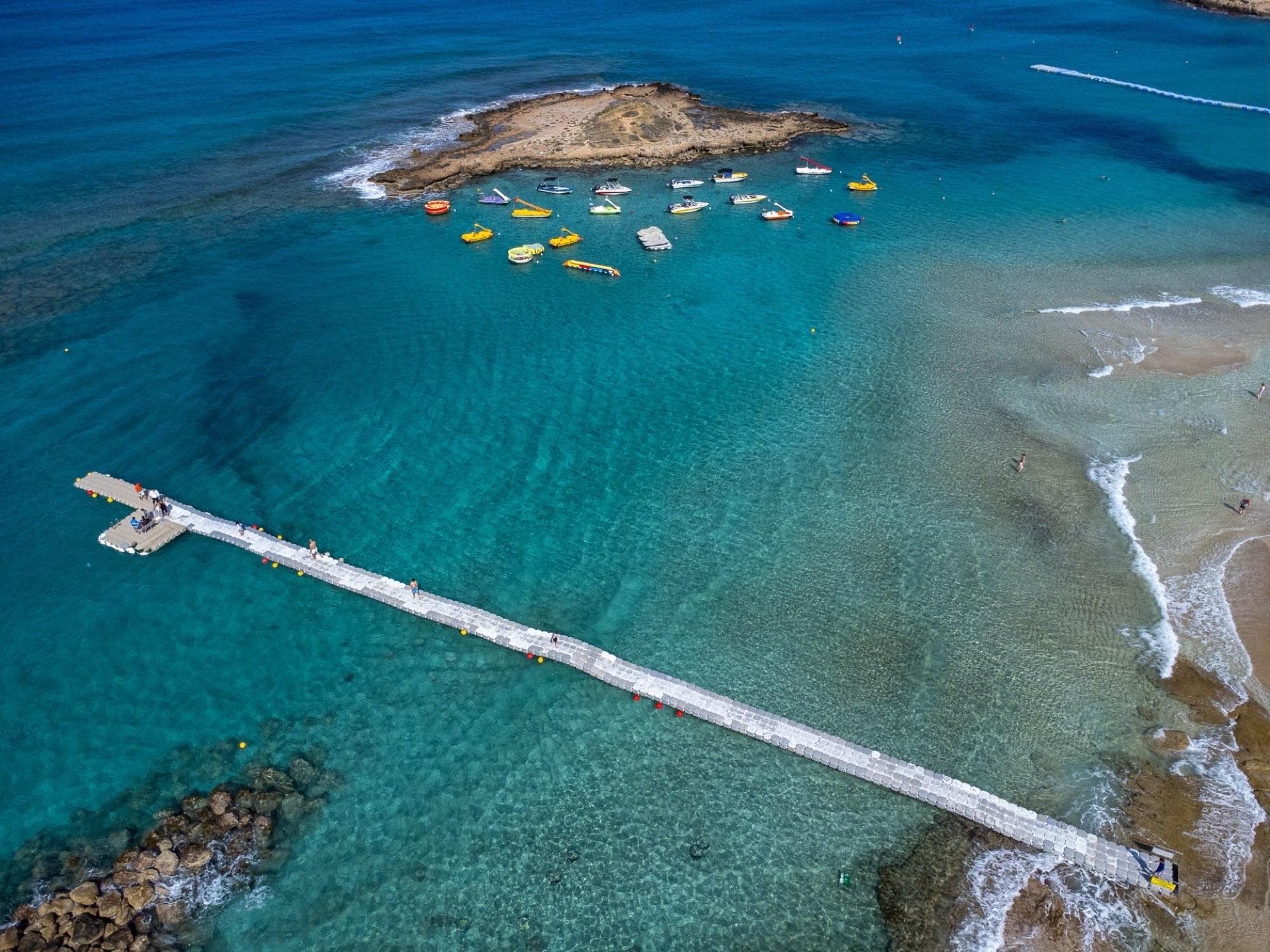 Aerial view of Fig Tree Bay's floating pontoon and anchored boats over turquoise water